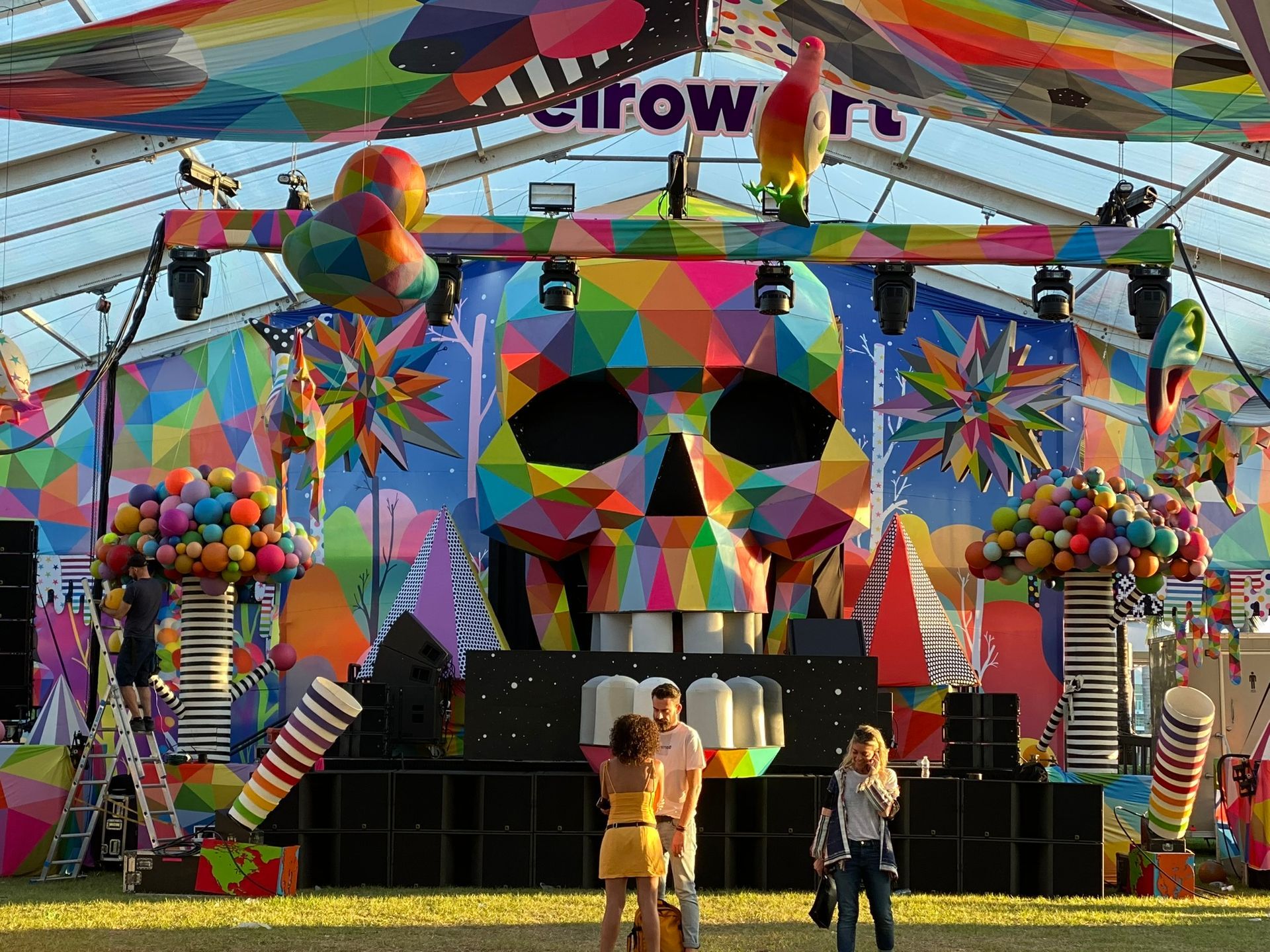 A group of people are standing in front of a colorful stage with a skull on it.