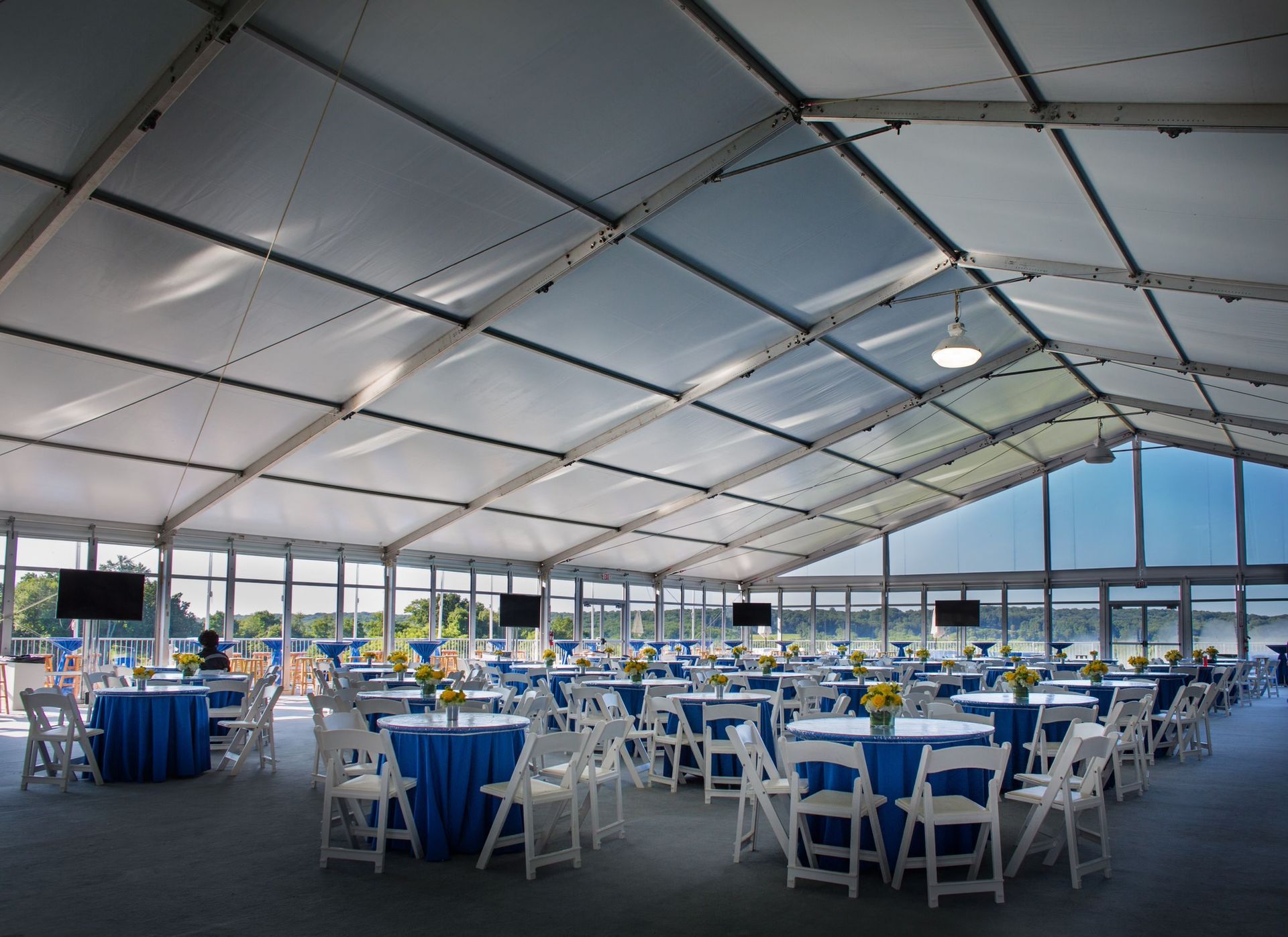 A large white tent with blue tables and chairs