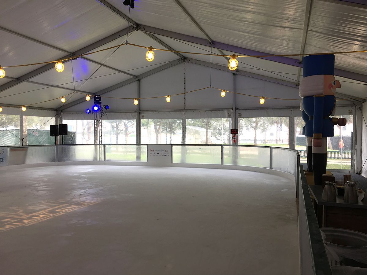 There is a large ice rink inside of a tent.