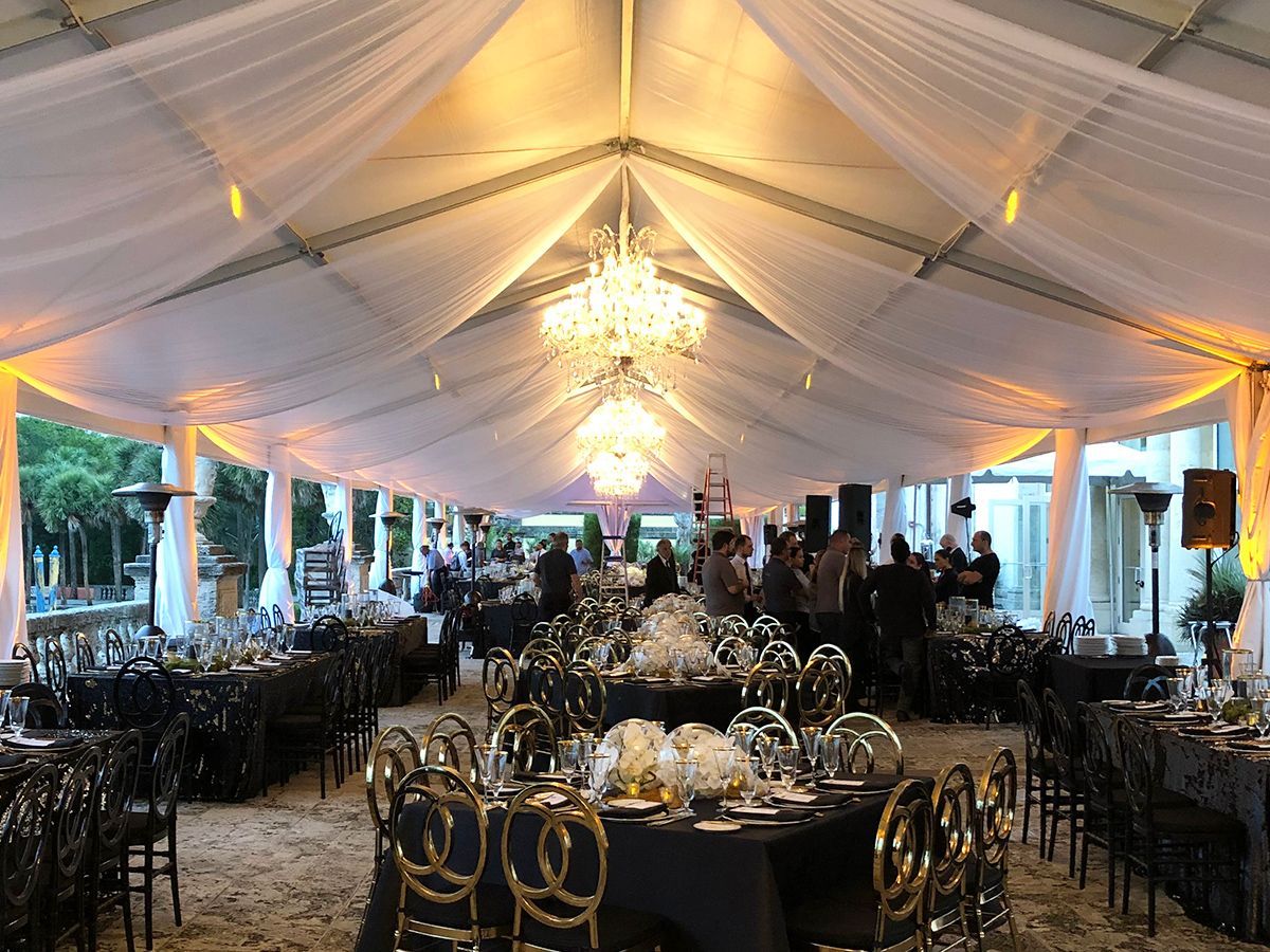 A large tent with tables and chairs set up for a wedding reception.