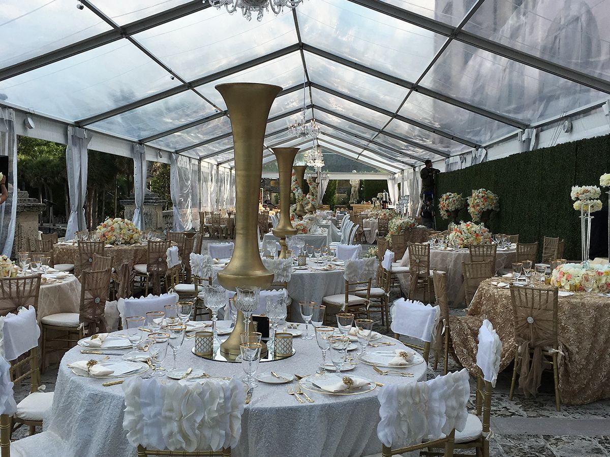 A large tent with tables and chairs set up for a wedding reception.