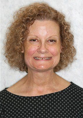 A woman with curly hair and braces on her teeth is smiling for the camera.
