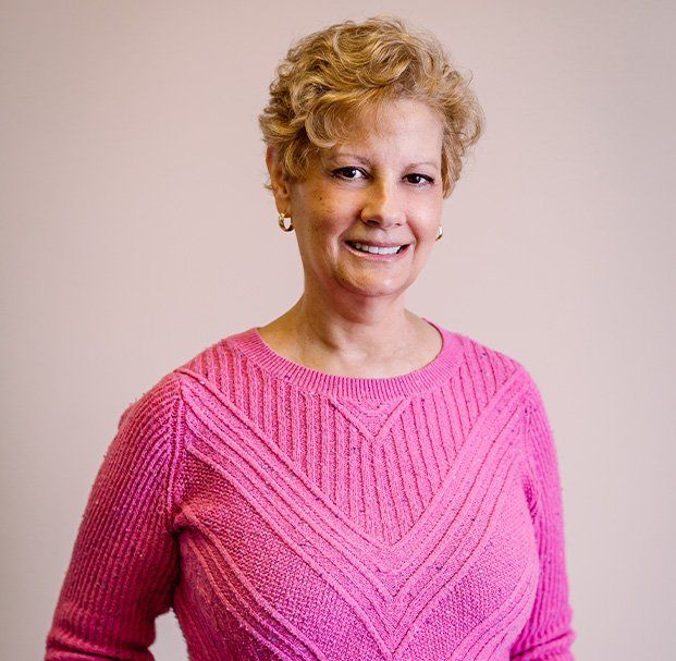 A woman in a pink sweater is smiling for the camera.