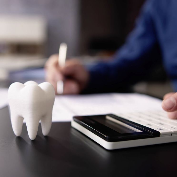 A tooth model is sitting on a table next to a calculator.