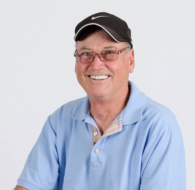 elder man with glasses and cap smiling