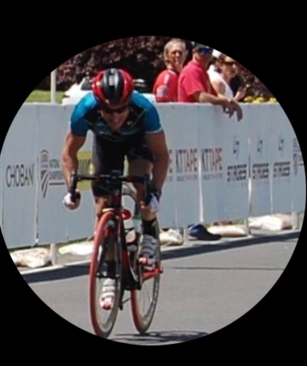 A man riding a bike in front of a fence that says choban