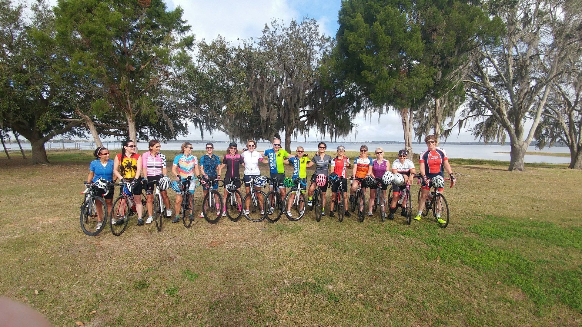 A group of people are posing for a picture with their bikes in a field.