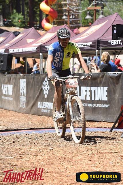 A man is riding a bike on a dirt road sponsored by lifetime