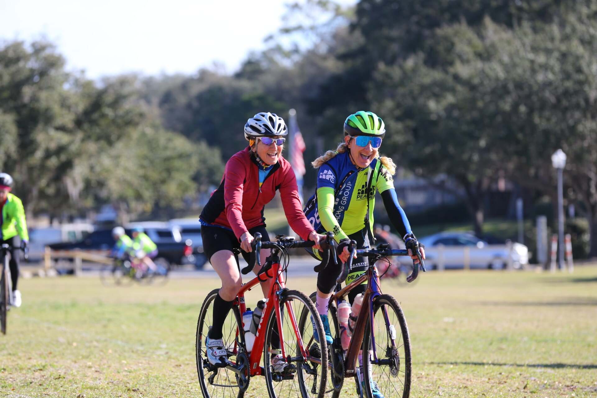 Two people are riding bicycles on a grassy field.