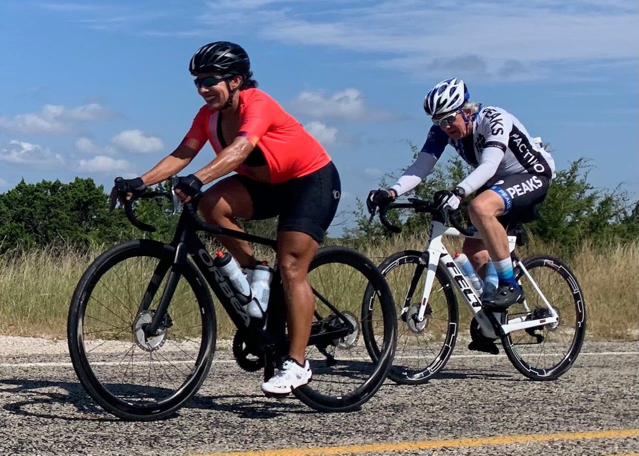 Two people are riding bicycles down a road.