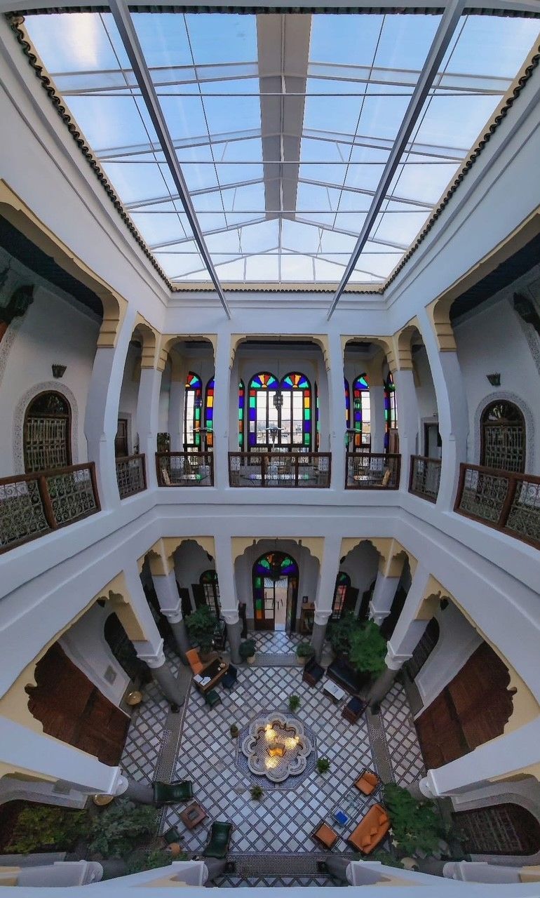 A large building with a glass ceiling and a fountain in the middle of it.