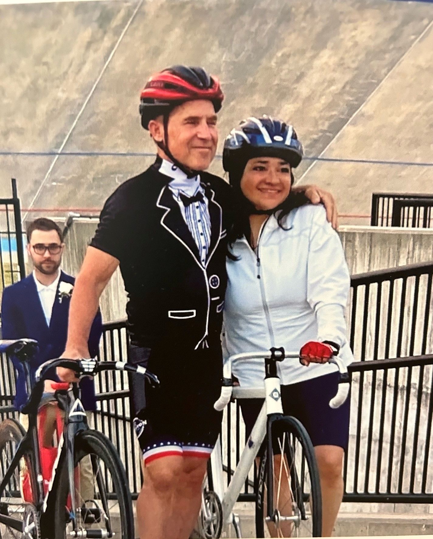A man in a tuxedo is standing next to a woman on a bike
