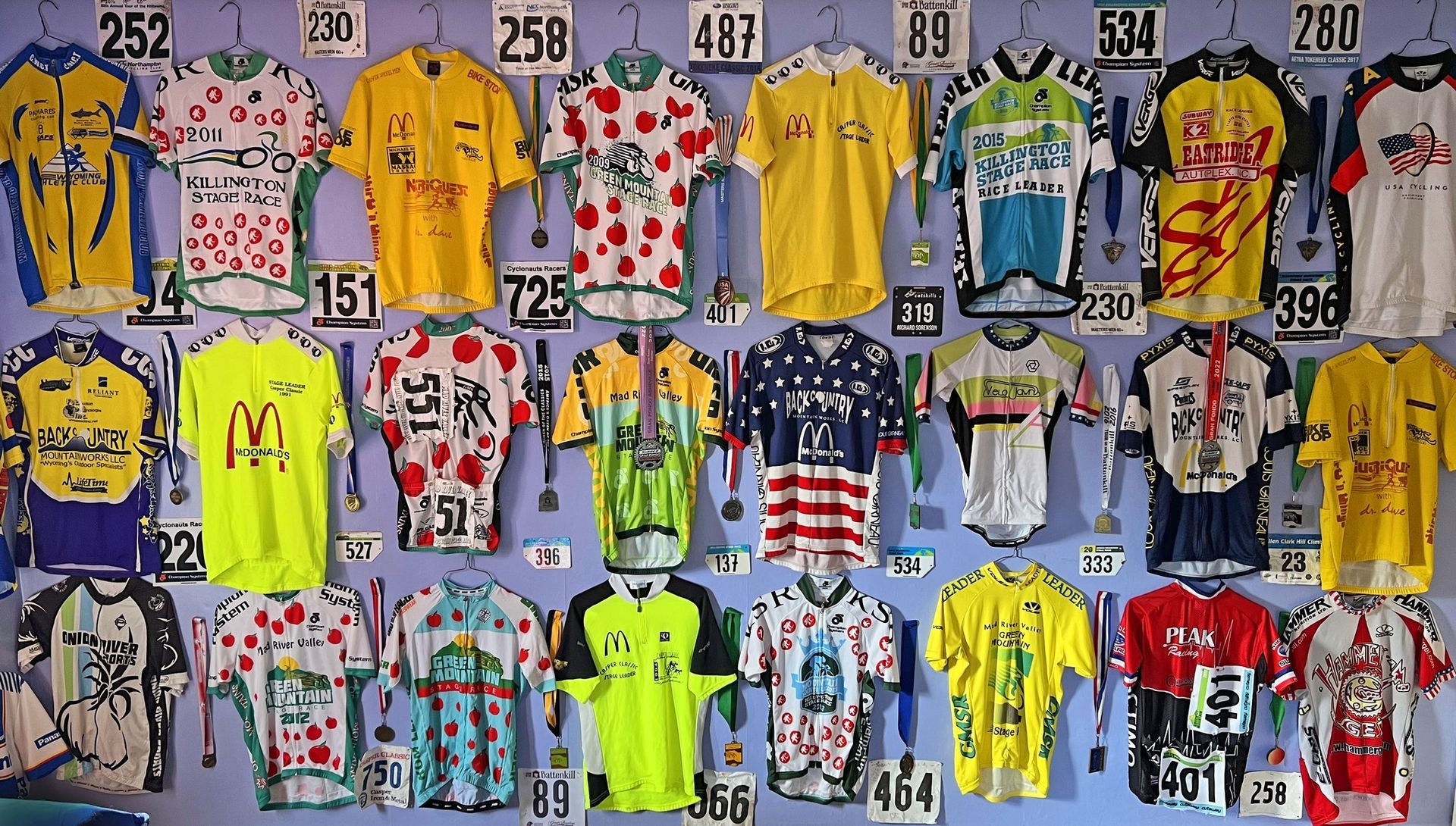 A bunch of shirts are hanging on a wall with numbers on them