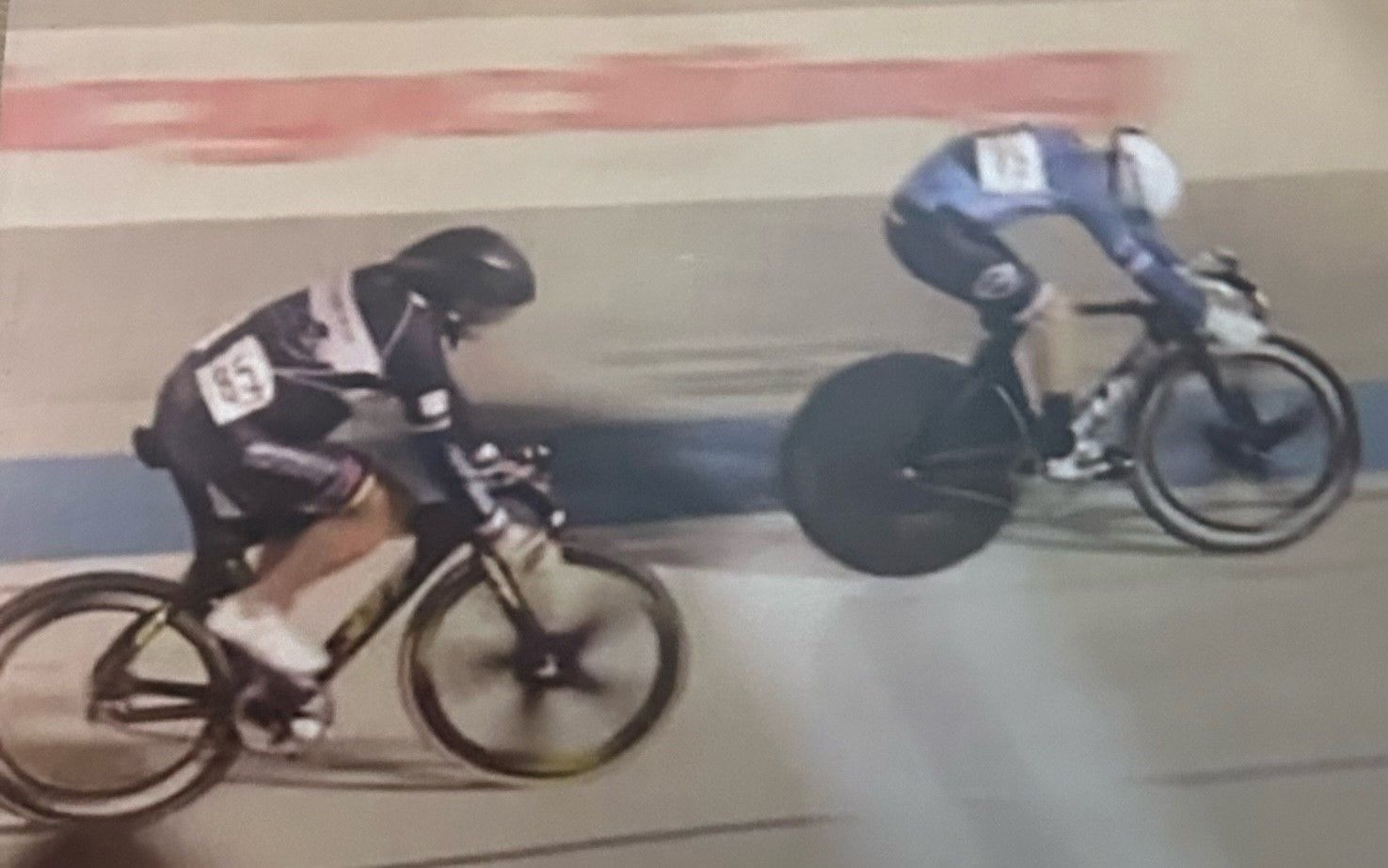 Two people are riding bicycles on a track.