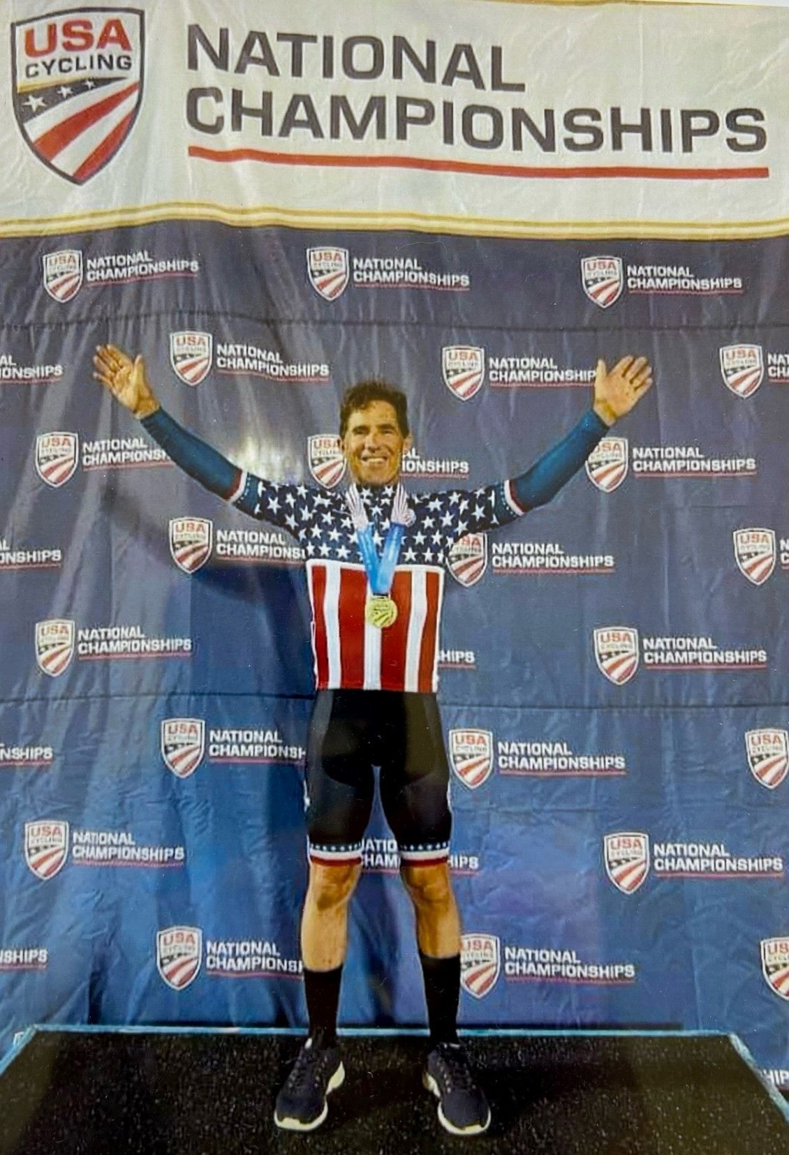 A man is standing in front of a usa cycling national championships banner