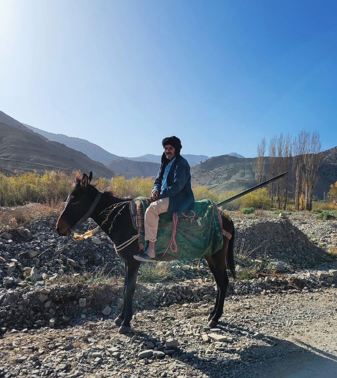 A man is riding a horse on a dirt road