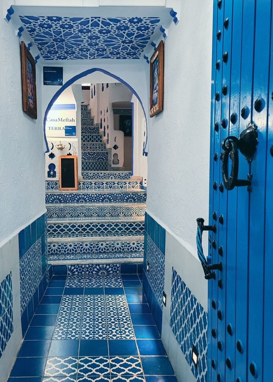 A hallway with blue and white tiles and a blue door