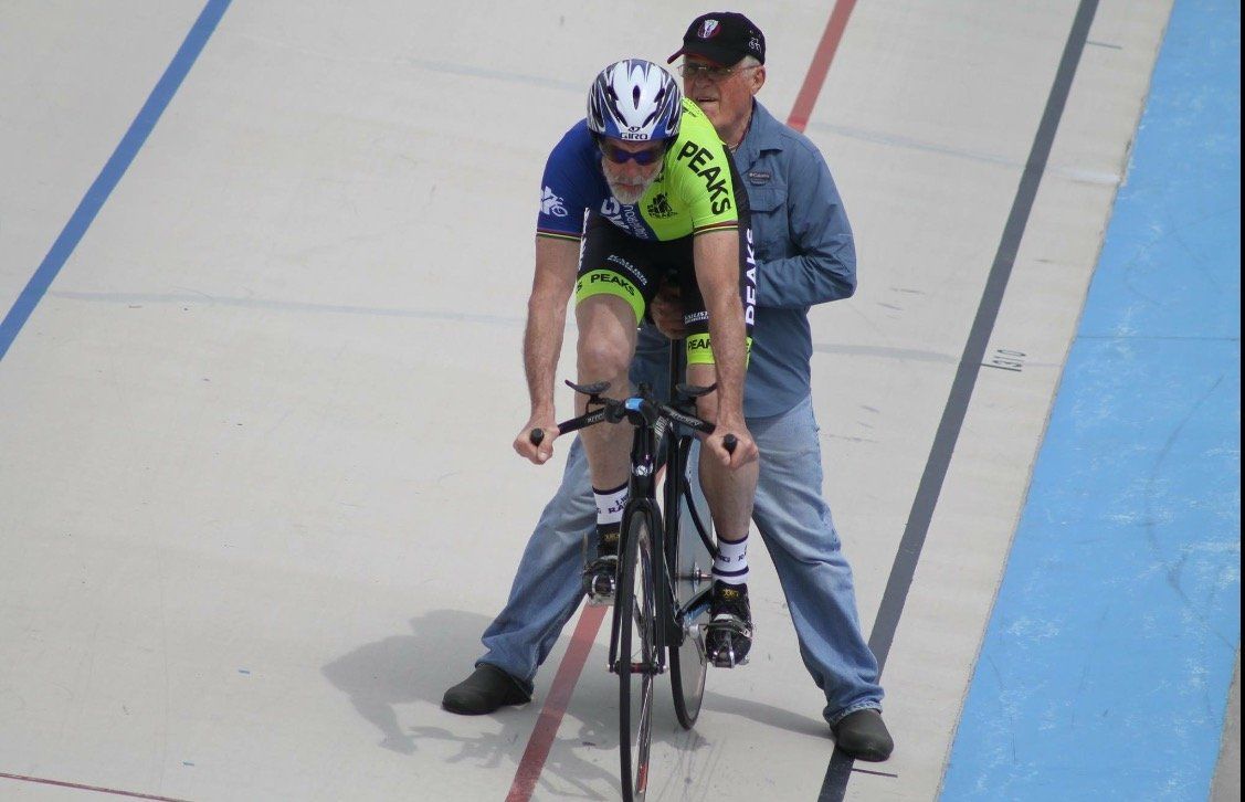 A man is standing next to a cyclist who is wearing a jersey that says bears