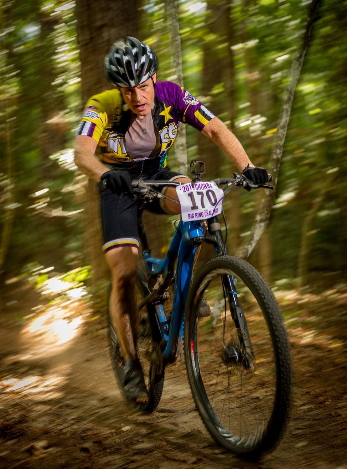 A man is riding a mountain bike down a trail in the woods.