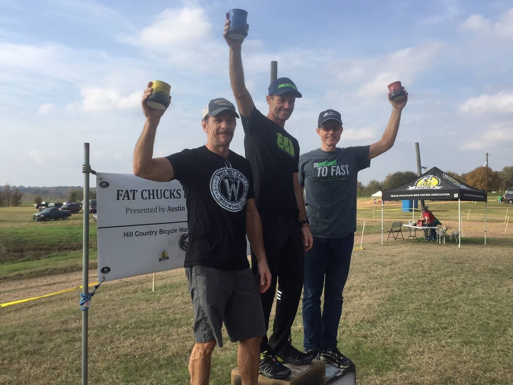 Three men are standing in front of a sign that says fast chicks