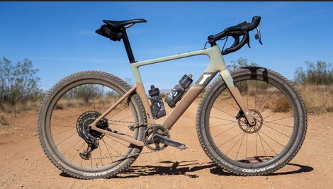 A bicycle is parked on a dirt road in the desert.