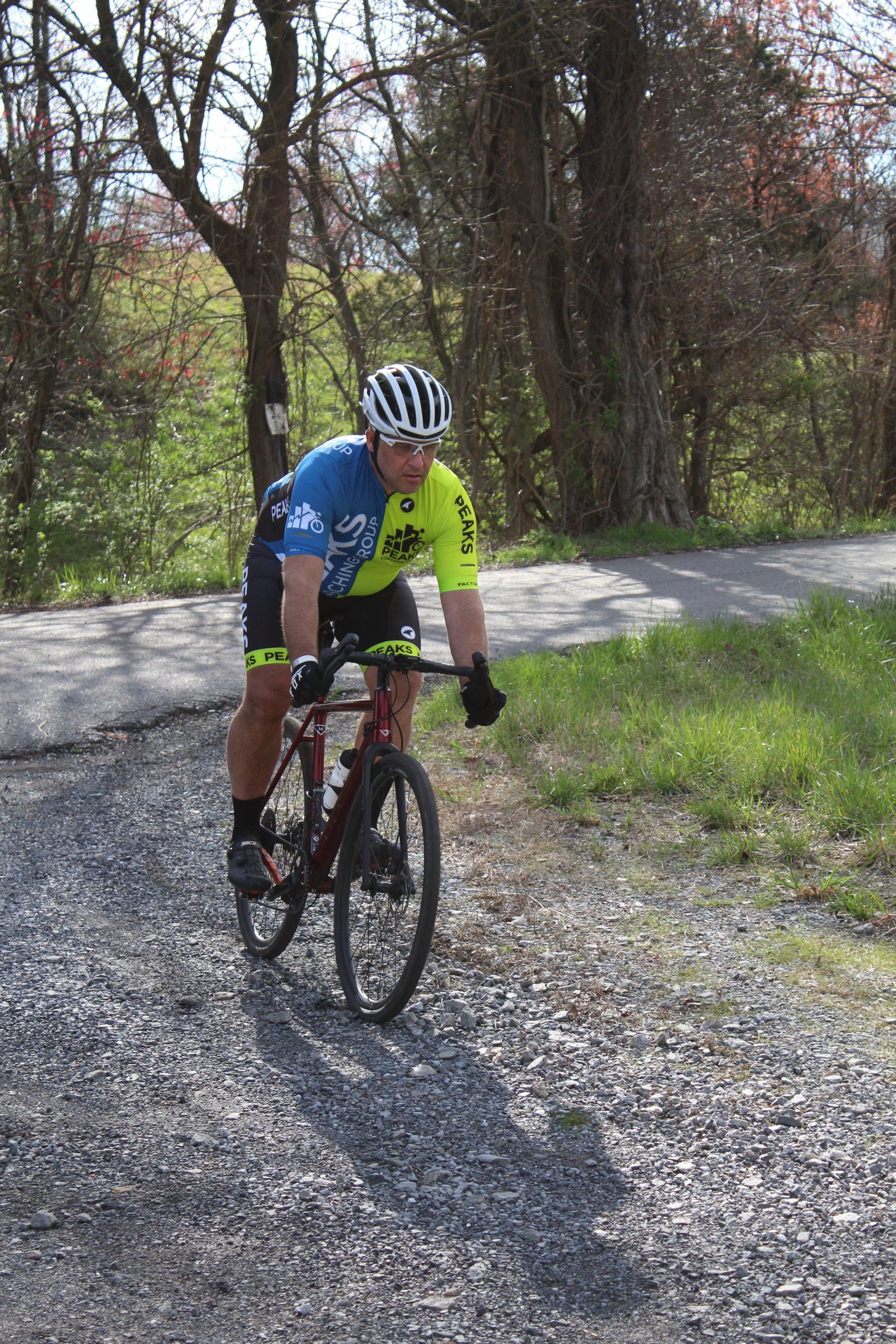 A man is riding a bike down a gravel road.