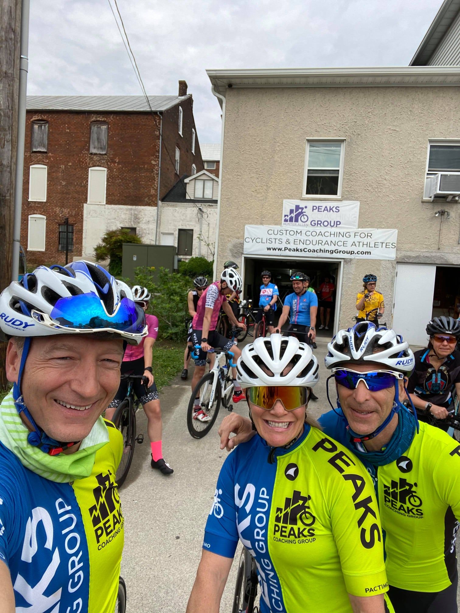 A group of cyclists are posing for a picture in front of a building.