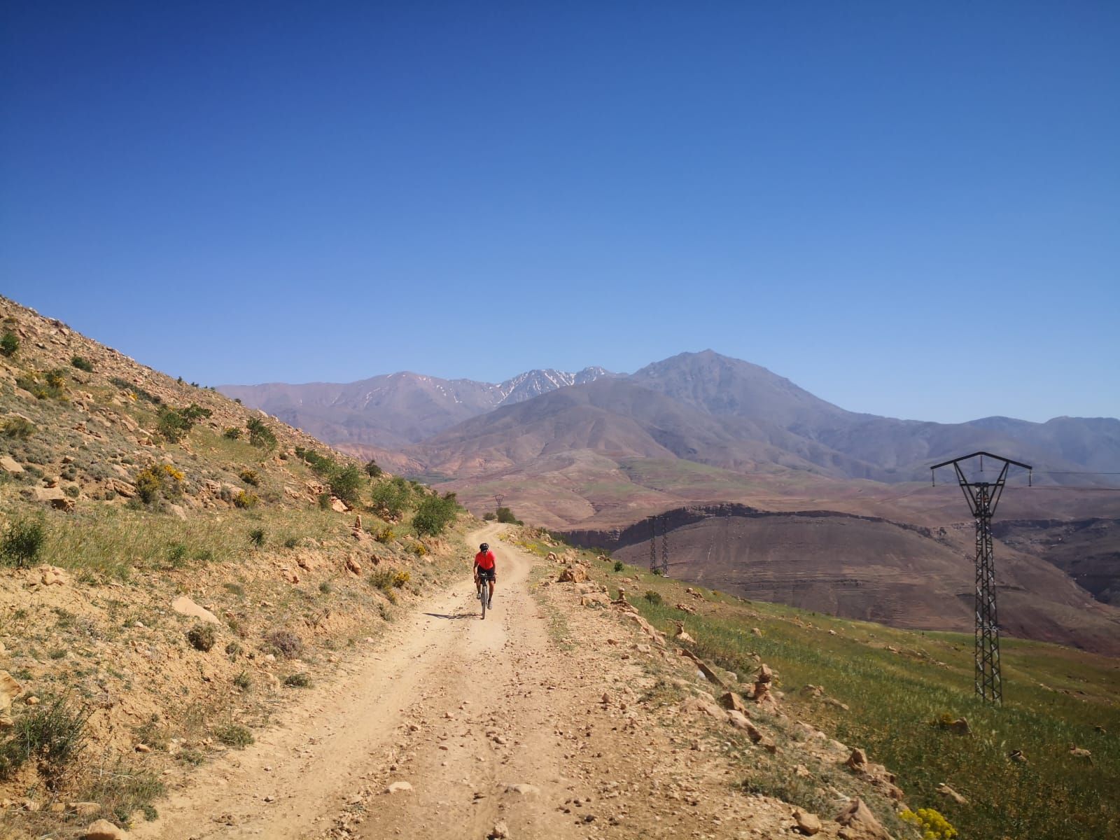 A person is riding a bike down a dirt road in the mountains.