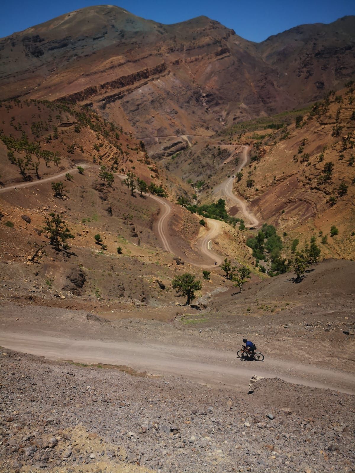 A person is riding a motorcycle down a dirt road in the mountains
