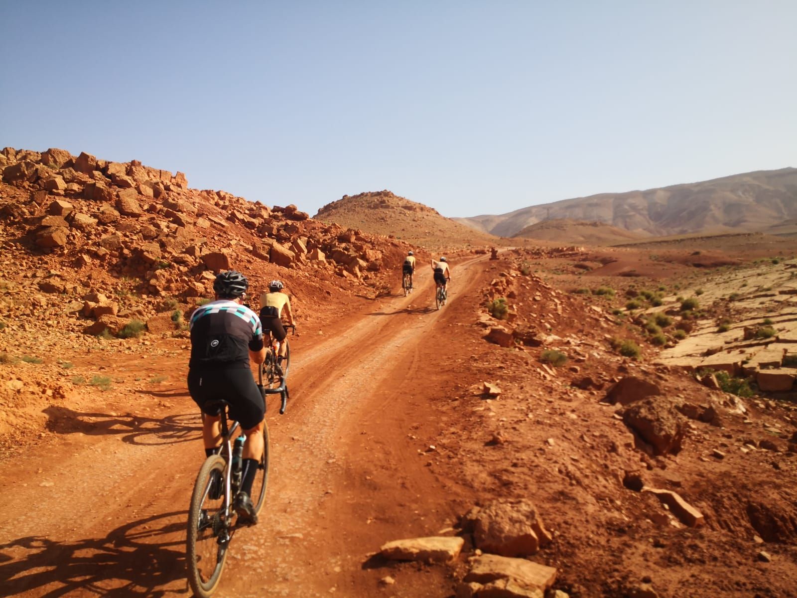 A group of people are riding bikes down a dirt road