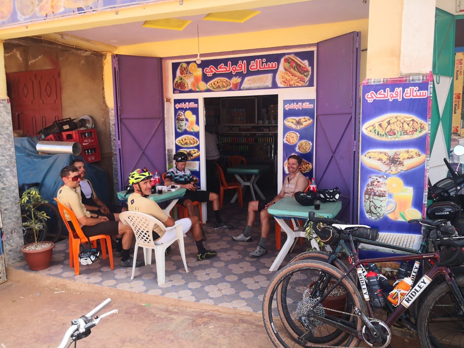 A group of people sit at tables outside of a restaurant