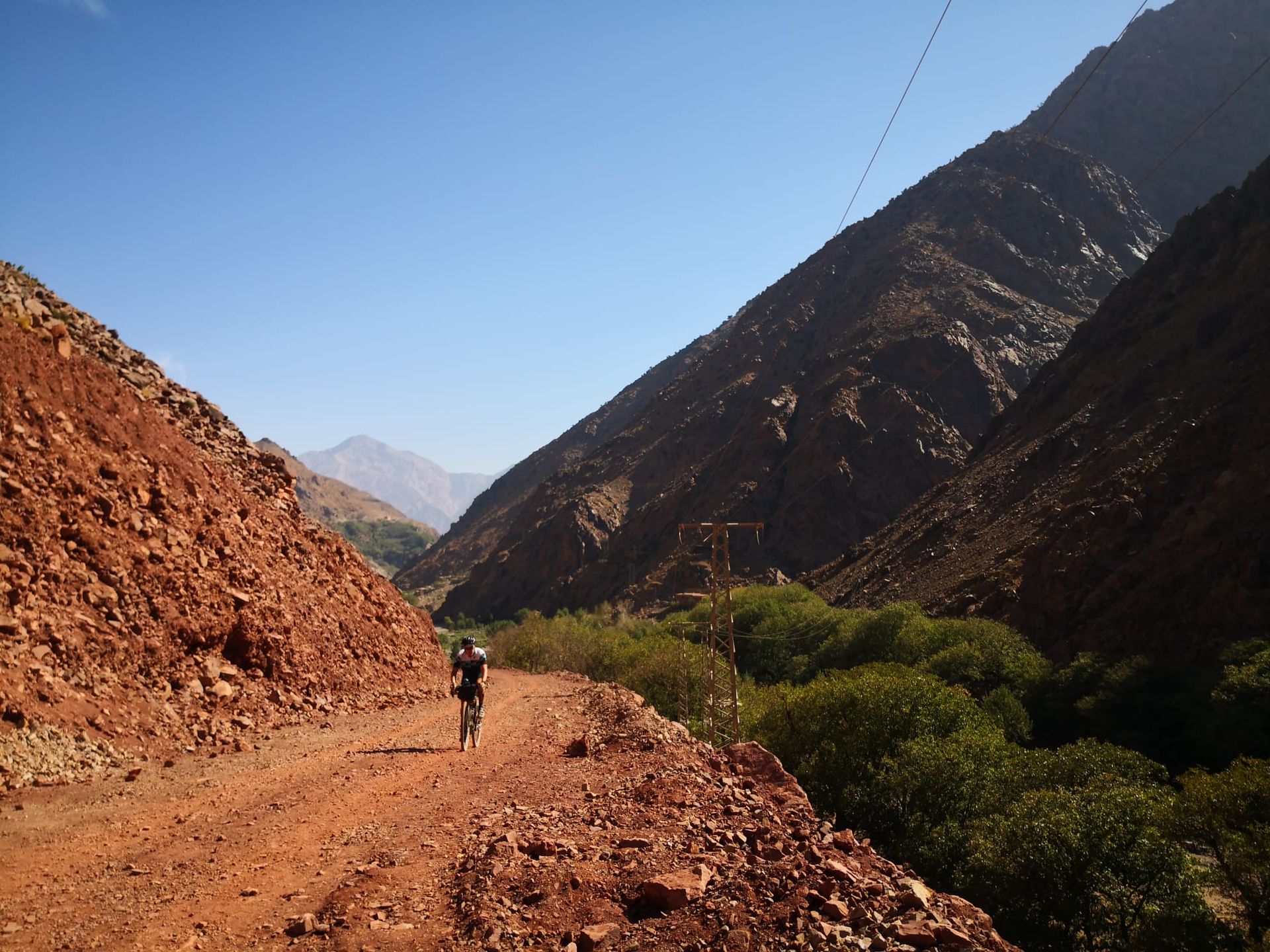 A person walking down a dirt road with mountains in the background