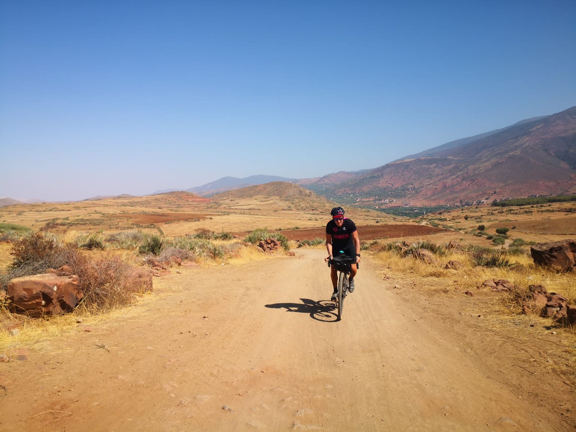 A man is riding a bike down a dirt road.
