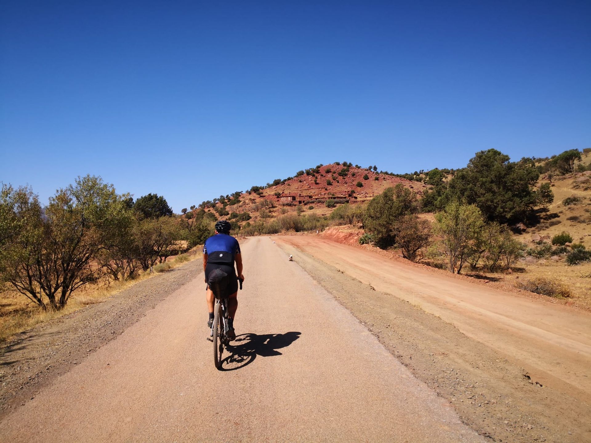 A person is riding a bike down a dirt road