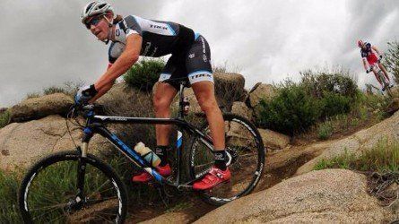 A man is riding a bike up a rocky hill.