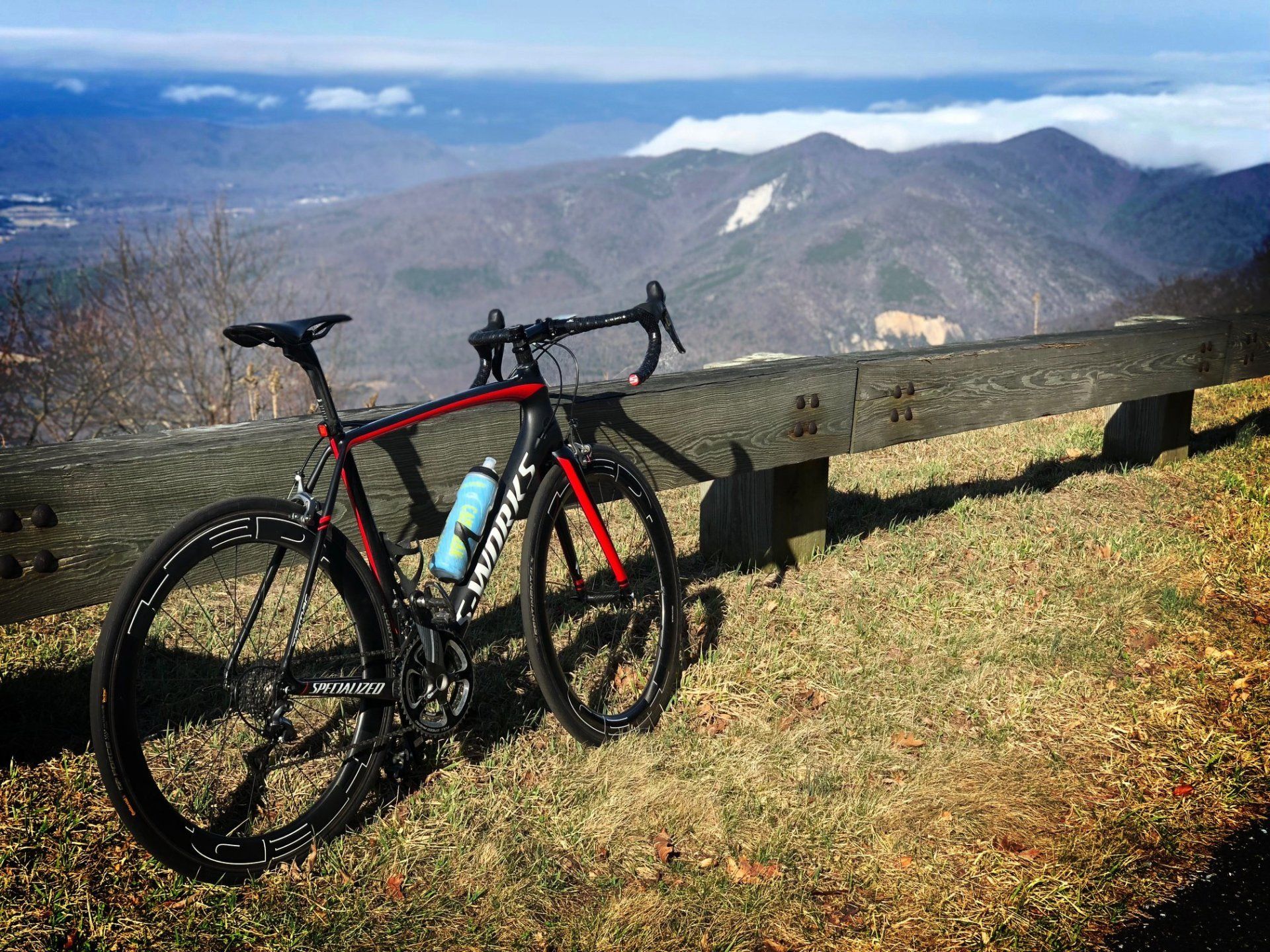 A bicycle is parked on a grassy hill with mountains in the background.
