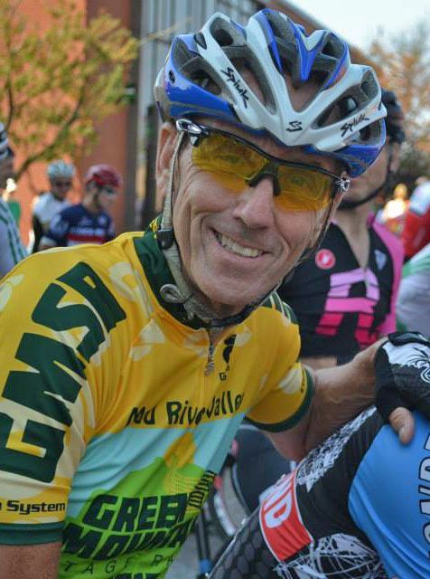 A man wearing a helmet and sunglasses is smiling for the camera