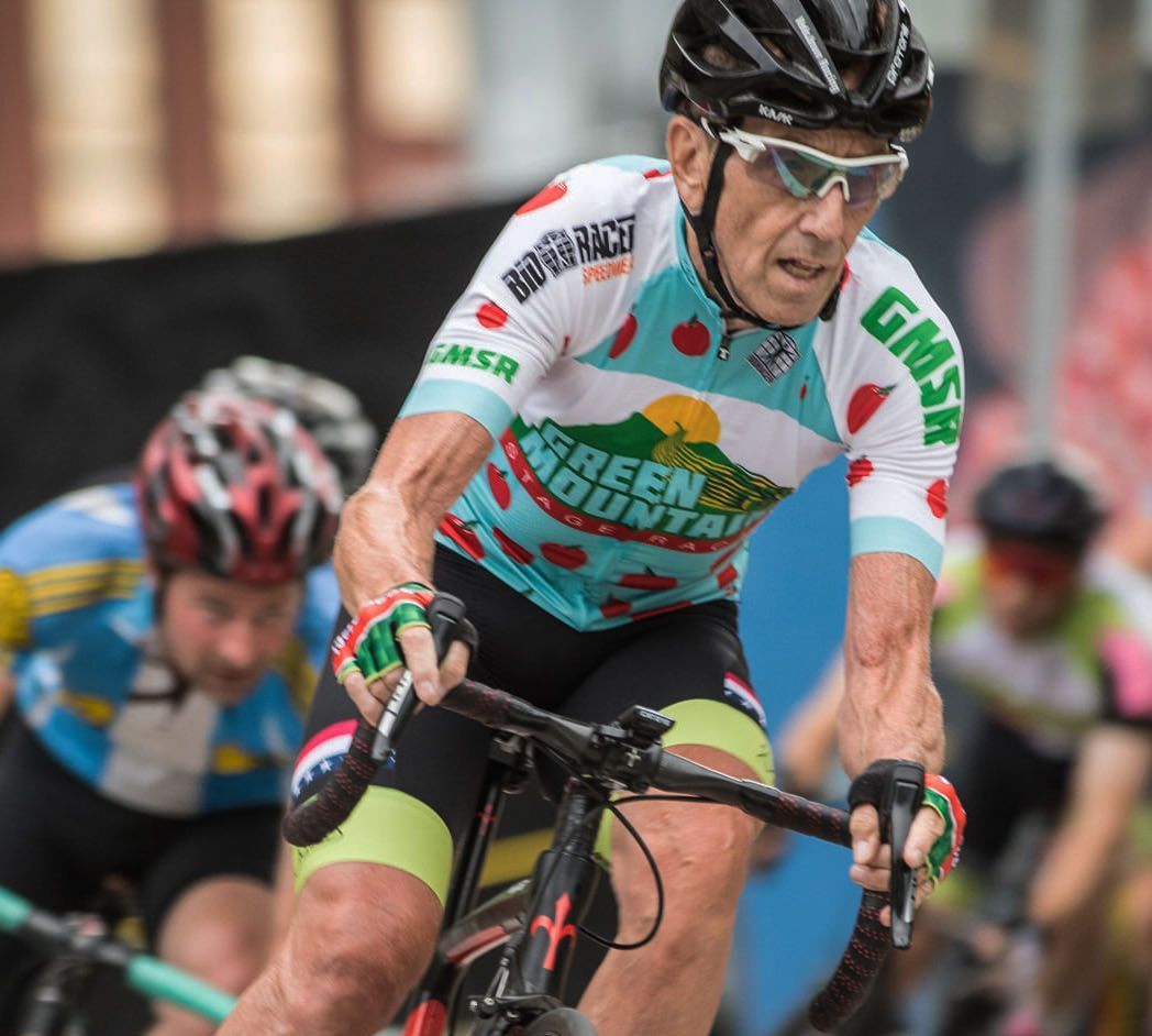 A man wearing a green mountain jersey is riding a bike