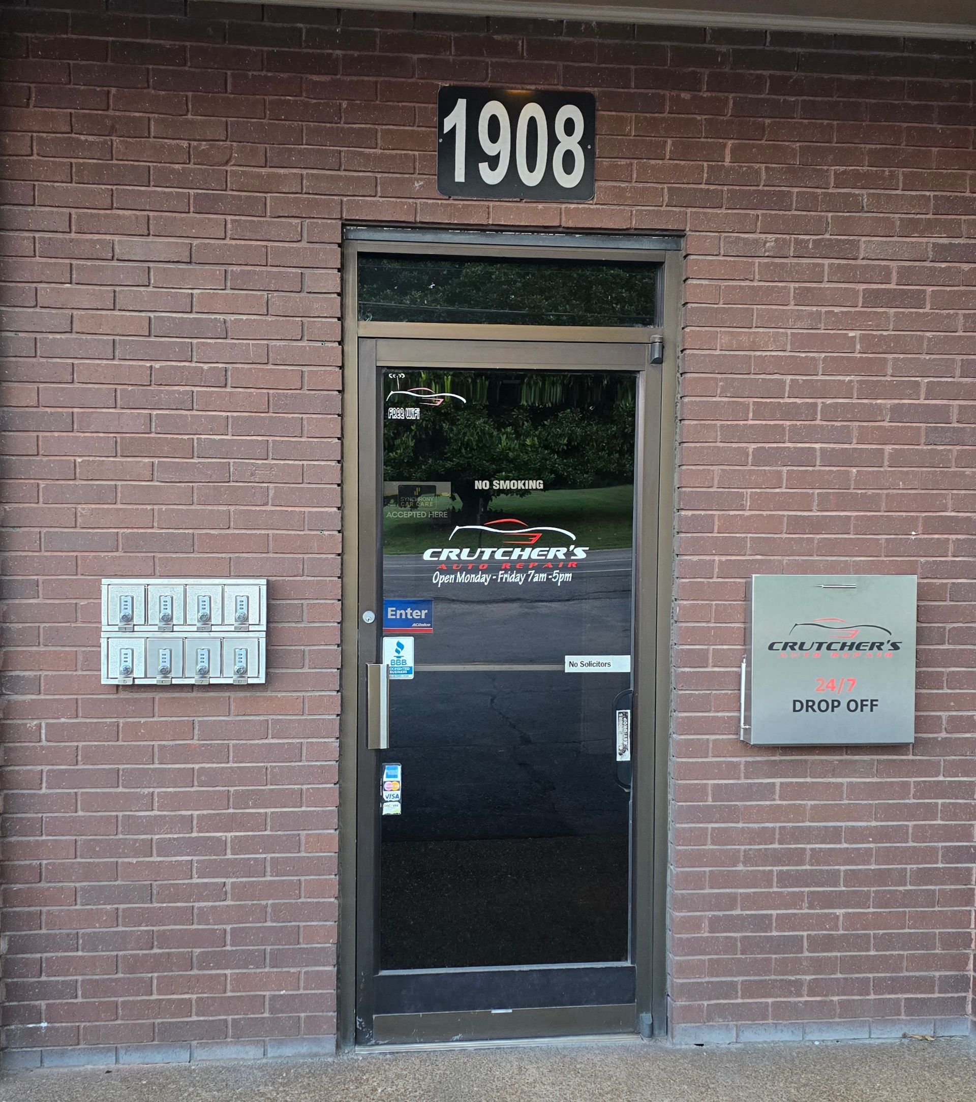 Brick building entrance, door with window, 1908 above. Mailboxes and access control on either side. | Crutcher's Auto Repair