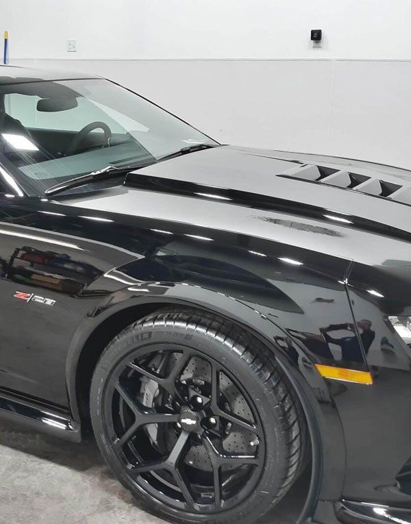 A black sports car is parked in a garage