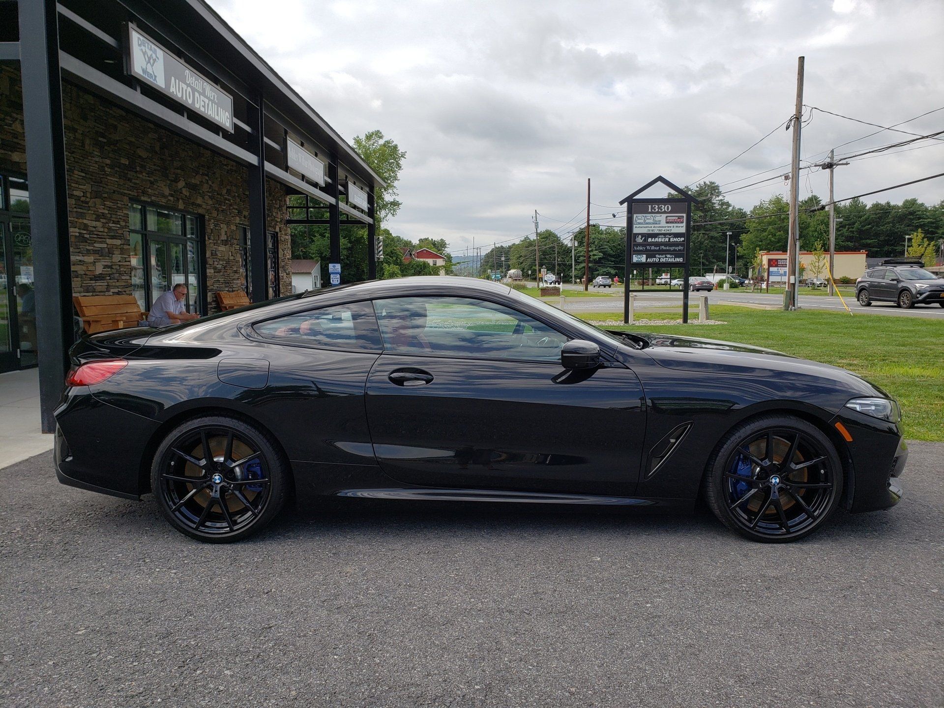 A black bmw 8 series coupe is parked in front of a building.
