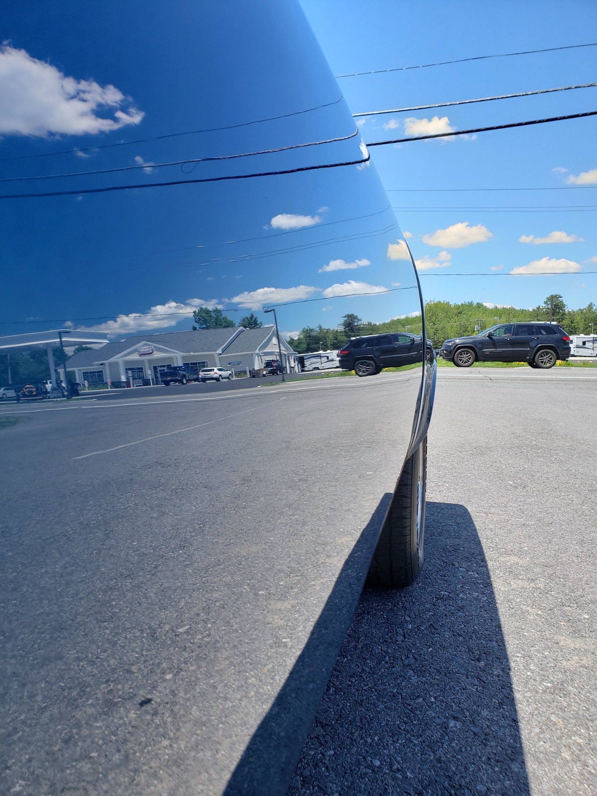 A blue car is parked on the side of the road in a parking lot.