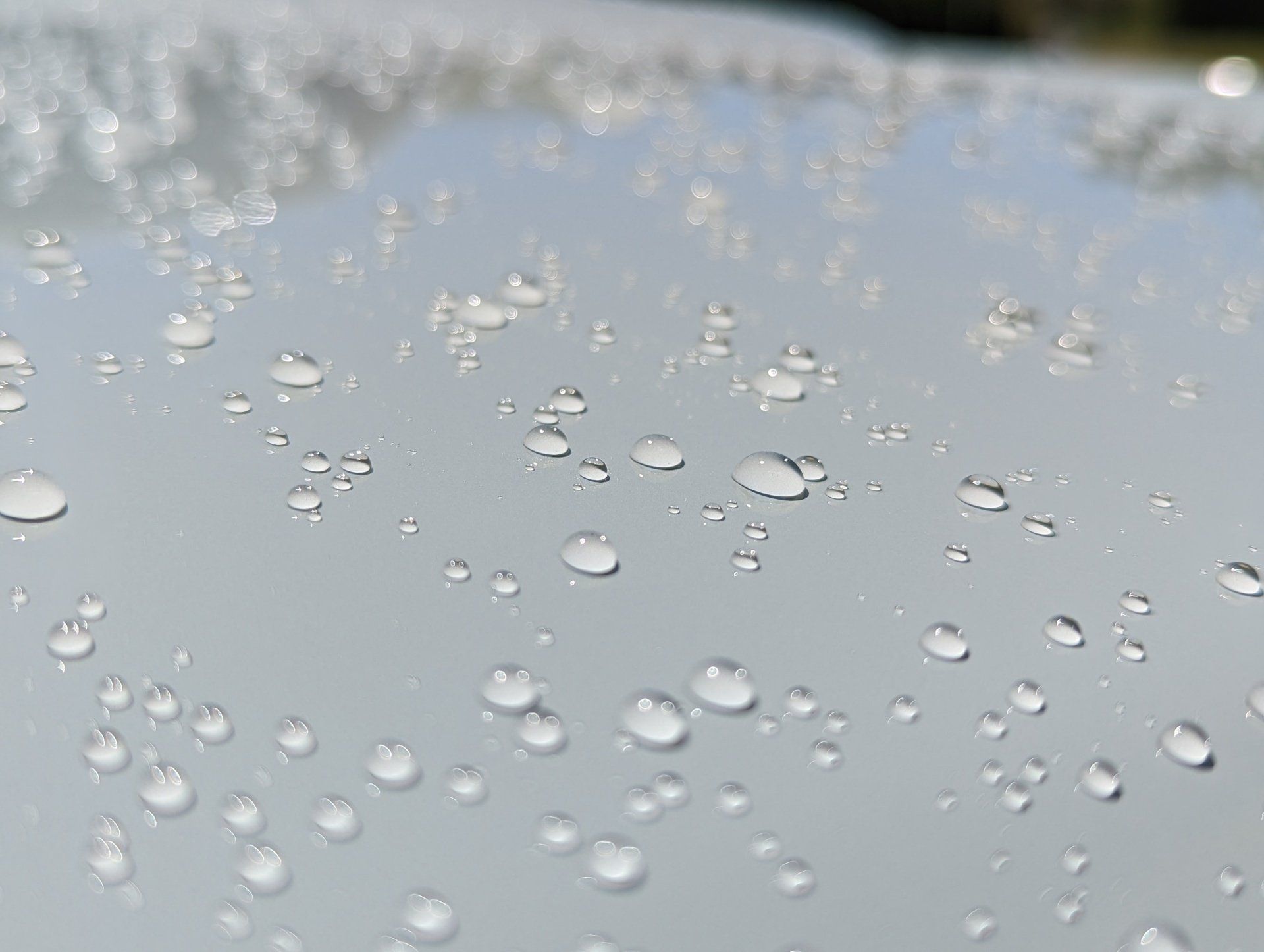 A close up of water drops on the hood of a car.