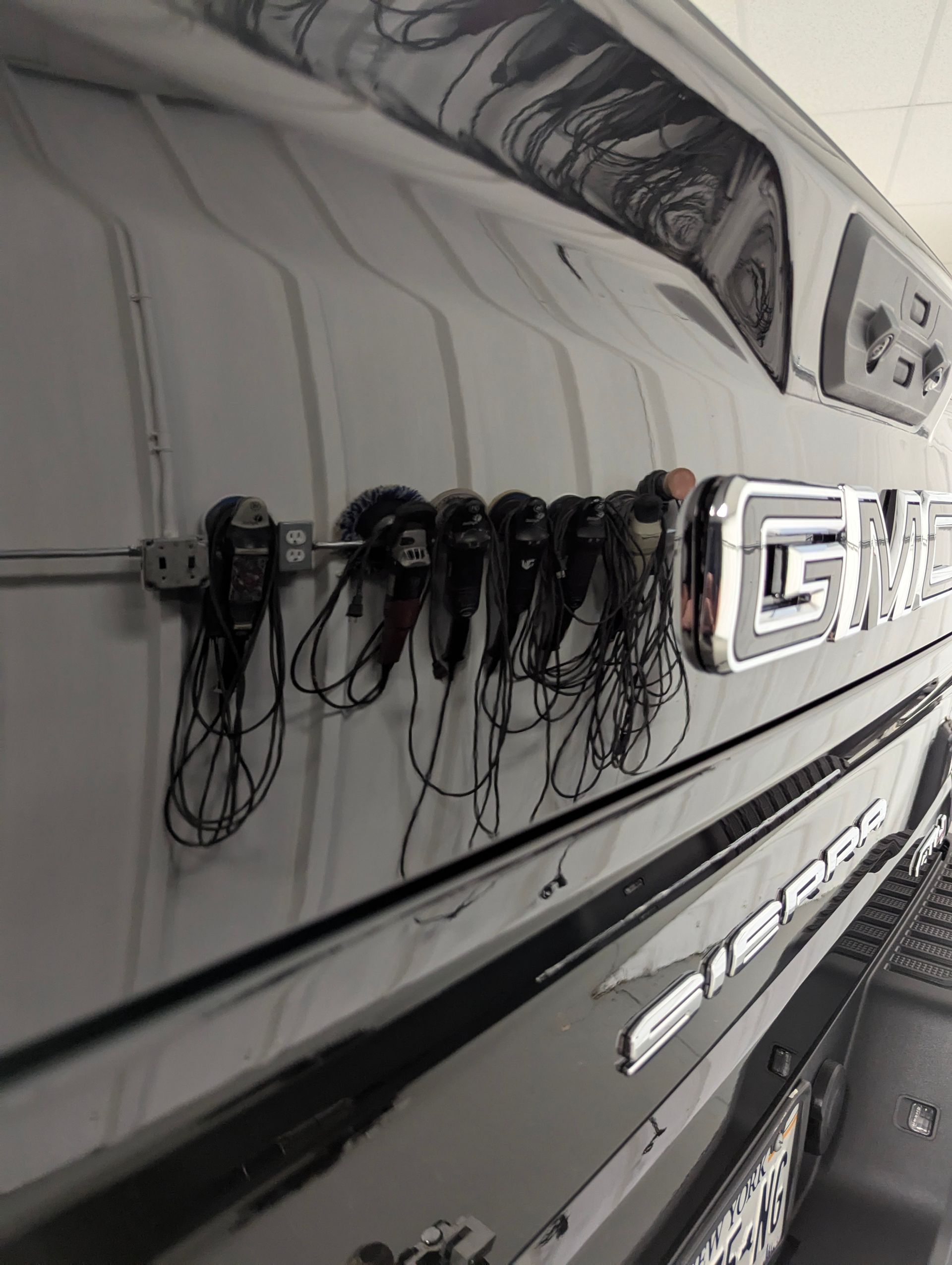 Black GMC Sierra truck bed with a rack holding multiple black microphone headsets.