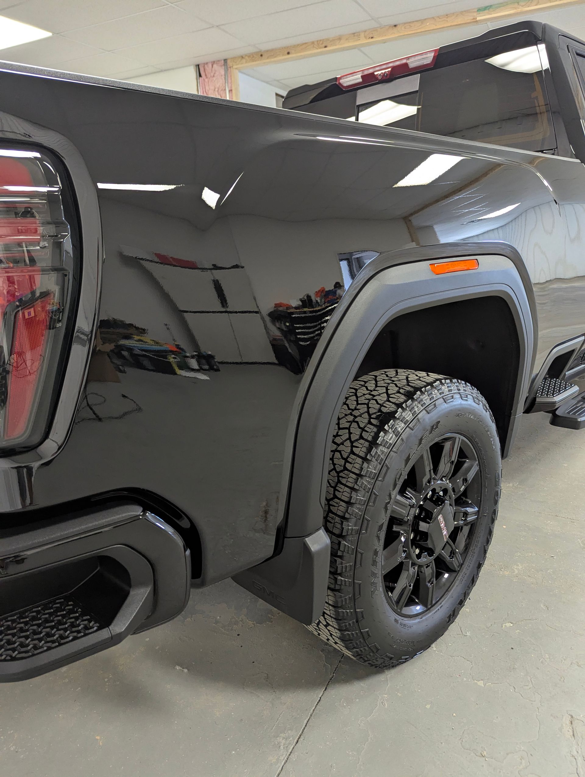 Black GMC truck rear quarter panel; black wheel and tire; black fender flares.