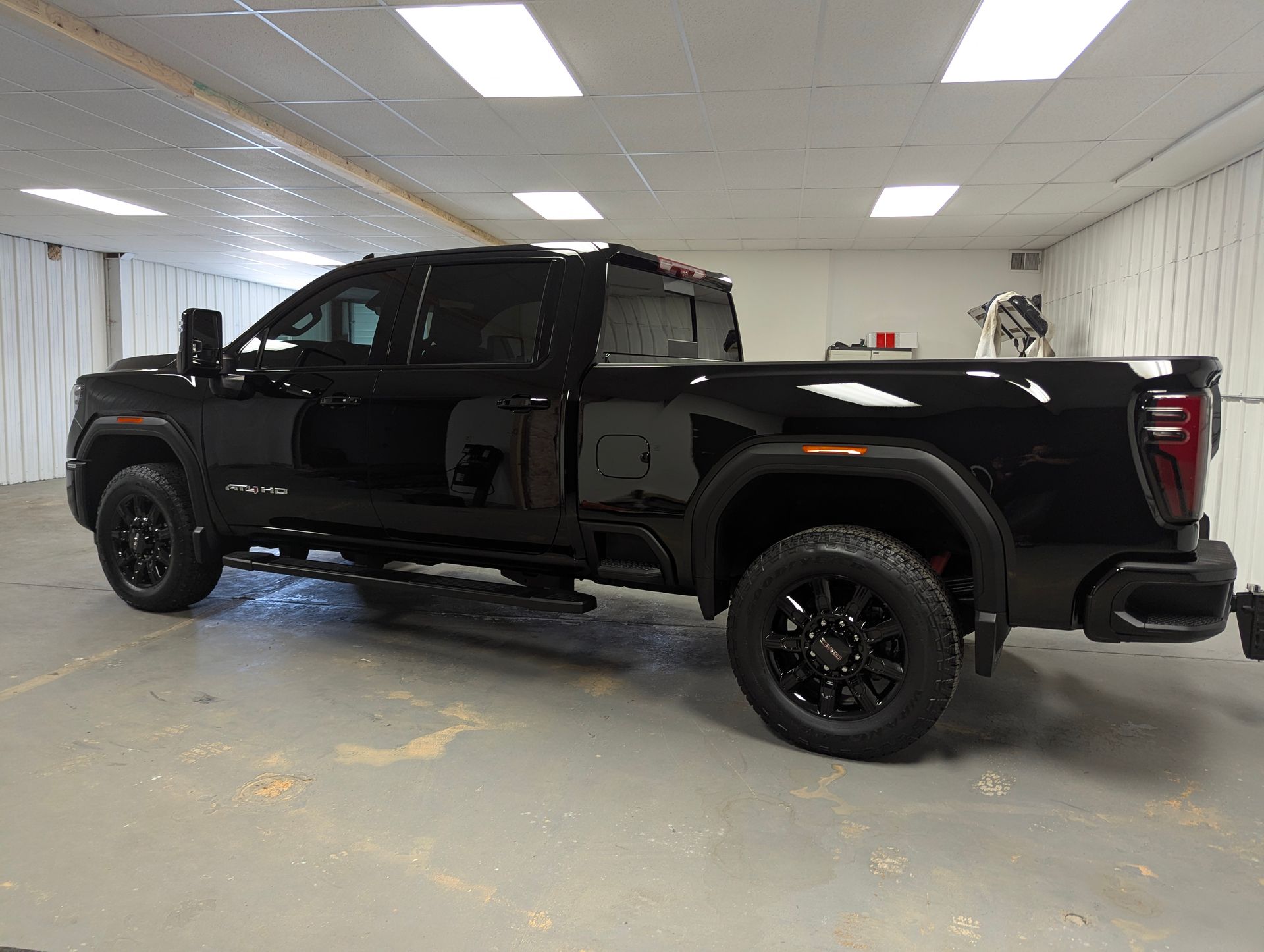 Black GMC truck parked inside a building with black wheels, and dark windows.