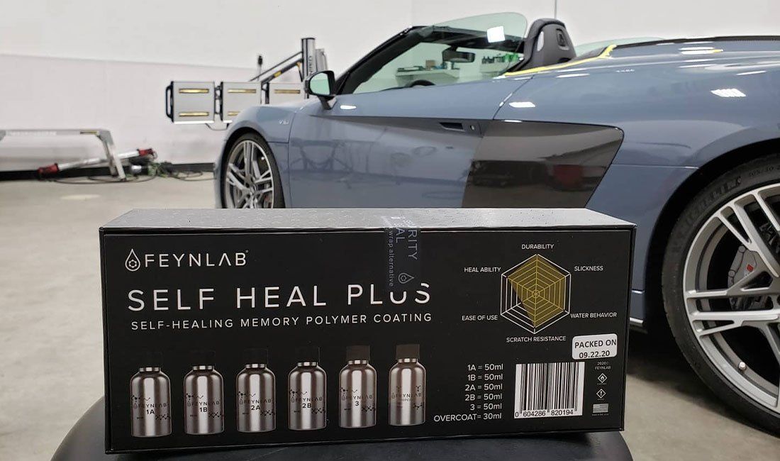 A blue sports car is parked next to a box that says self heal plus