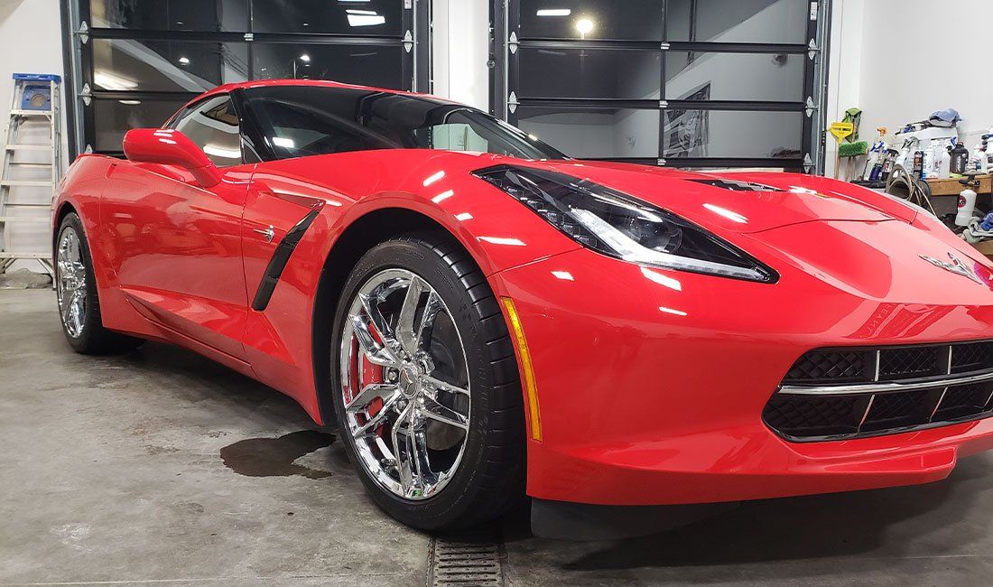 A red sports car is parked in a garage.