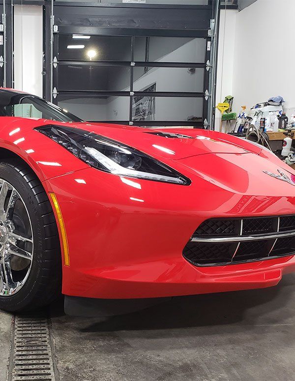 A red sports car is parked in a garage