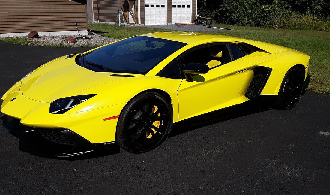 A yellow lamborghini aventador is parked in a driveway.
